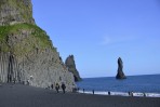Der schwarze Sandstrand Dyrhlaey mit Menschen die auf grauen Basalsulen klettern